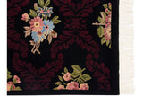 Carved burgundy leaves and pastel florals on a black Aubusson design carpet with ivory fringe.