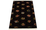 Angled view of the floral blossoms and dark trellis pattern on an Indian Aubusson carpet.