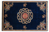 Carved floral bouquet in a rattan vase on the cobalt blue field of a vintage Indian carpet.