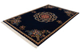 Angled view of the vintage Indian carpet's Aubusson design with floral bouquets in rattan vases.