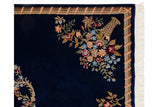 Carved floral bouquet in a rattan vase on the corner of an Aubusson design rug.