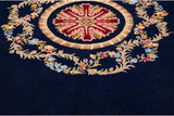 Carved texture of the floral medallion in rose and blue on a deep cobalt wool pile.