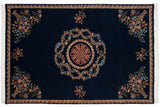 Floral bouquets in rattan vases adorn the corners of a cobalt blue vintage Aubusson carpet.