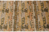 Textured hand-knotted pile with layered primitive abstract shapes in olive, gold, and tangerine.