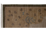 Corner view of Indian folk art carpet, fringed dark olive border, carved slate blue detail.