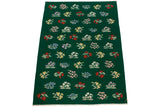 Colorful floral blossoms and bouquets in a diagonal pattern on a forest green Kilim with fringe.
