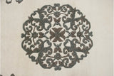 Shallow carved floral motif detail in ivory and muted grey on a vintage Peking rug.