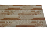 Angled detail of abstract Indian Soumac carpet with beige and copper ripple circles.