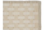 Close-up of flatweave Indian Basketweave Soumac rug corner, ivory and sand tones, banded border.