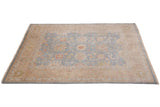 Corner of Indian Oushak rug with oversized palmettes on dusty blue field, beige border.