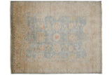 Upper right corner of Oushak rug showing dusty blue field, floral palmettes, wheat border, and selvage.