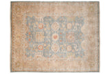 Corner of Indian Oushak rug with blue floral field and wheat border.
