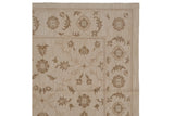Rococo stylized floral arabesques at the corner of an ivory and brown Indian Soumac carpet.