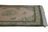 Cream fringe end with moss green border detail on the vintage Peking rug.