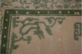 Corner of vintage Indian Peking rug: moss green border, star motifs, ivory field, white knots.