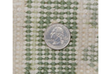 Hand-knotted pile texture with ivory and moss green diamond pattern, quarter for scale.