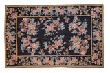 Vintage chainstitch rug with rose and copper floral bouquets on a black field with a floral border.