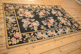 Vintage floral chainstitch rug with rose bouquets on a black field, viewed from a high angle.