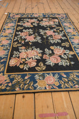 Black chainstitch field with dusty rose bouquets, accented by a sapphire blue floral border.