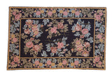 Vintage chainstitch rug with rose and copper floral bouquets on a black field, framed in saffron yellow.