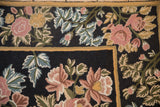 Detailed corner view of a vintage chainstitch rug's rose and blue floral pattern.