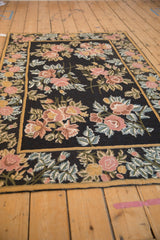 Angled corner view of a vintage chainstitch rug with floral bouquets and a saffron yellow border.