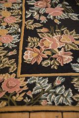 Detailed chainstitch weave of rose and saffron floral bouquets on a black field rug.