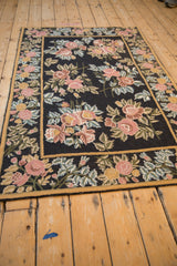 Angled view down the length of a floral chainstitch rug with a black field.