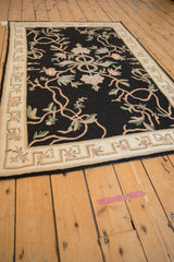 Angled perspective of a vintage chainstitch rug with a central ribbon and sprawling floral vines.