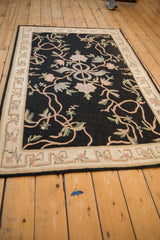Low angle view of a vintage chainstitch rug, showing the sprawling vine pattern on a black field.
