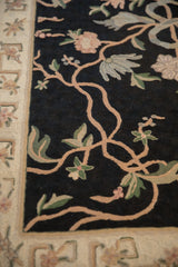 Detail of the sprawling vine motif in chainstitch on a black field beside a floral ivory border.