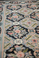 Raised chainstitch texture of Savonnerie-inspired florals in powder blue and rose on a black vintage rug.