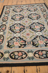 Perspective view of a vintage chainstitch rug's floral field and decorative multi-panel border.