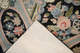 Folded corner of a vintage chainstitch rug showing the floral weave and clean backing.