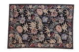 Vintage chainstitch rug with a curvilinear floral pattern in dusty rose, blue, and sand on a black field.