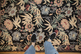 Spiraling chainstitch texture on a vintage floral rug with a black field.