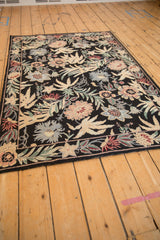 Angled view of a vintage chainstitch rug displaying its intricate, curvilinear floral pattern.