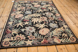 An angled perspective of the vintage chainstitch rug, highlighting the full floral and foliate pattern against a black ground.