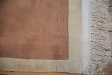Pale coffee brown copper field, shallow carved contour, ivory border, and cream fringe detail.