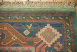 Vintage Indian Caucasian rug corner with geometric border, dusty blue, terracotta, and green.
