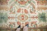 Softened ivory pile with jade green and terracotta floral palmettes on a vintage Indian Caucasian rug.
