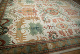 Indian Caucasian design rug section: ivory field, blush floral palmettes, jade leaves, ornate border.