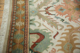 Ivory fringe, geometric border in gold and terracotta, and field's jade green palmette motifs.
