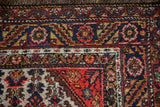 Close-up on the navy blue main border with red floral and serrated leaf motifs.