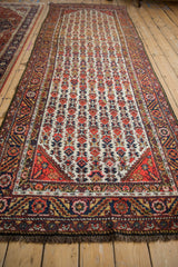 Angled perspective of a vintage Hamadan runner with a repeating floral and serrated leaf design.