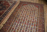 Vintage Persian Hamadan runner displayed full length on a wood floor beside another rug.