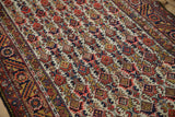 Hand-knotted pile showing serrated leaf and blossom motifs in red, navy, and saffron.