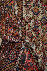 A vintage Hamadan rug draped to show its textured pile and intricate floral borders.