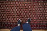 Overhead perspective of a vintage Ardebil runner's repeating cherry red floral lattice pattern.