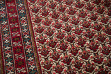 Detail of the Ardebil runner's plush pile, showing the floral lattice and red border.